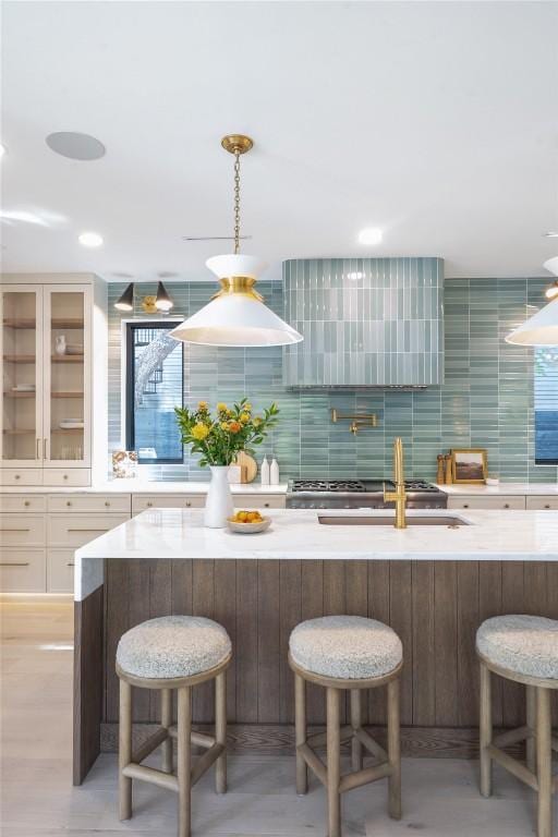 kitchen with hanging light fixtures, decorative backsplash, sink, and a kitchen bar