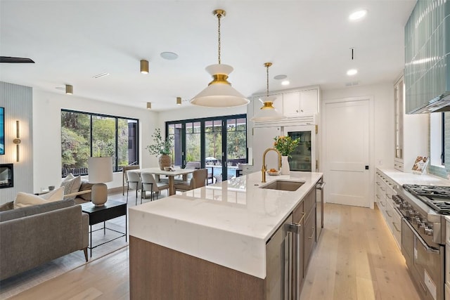 kitchen featuring white cabinetry, sink, pendant lighting, and light hardwood / wood-style floors