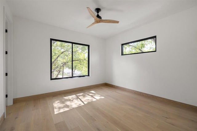 empty room with ceiling fan, a wealth of natural light, and light hardwood / wood-style floors