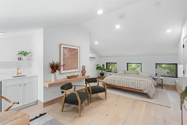 bedroom with sink, a wall mounted air conditioner, vaulted ceiling, and light wood-type flooring