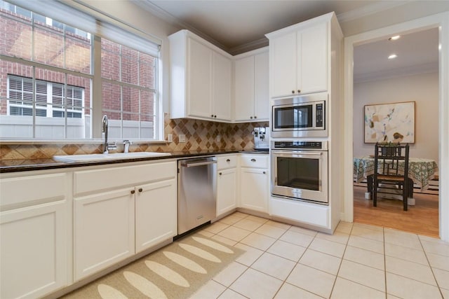 kitchen featuring white cabinets, sink, ornamental molding, and stainless steel appliances