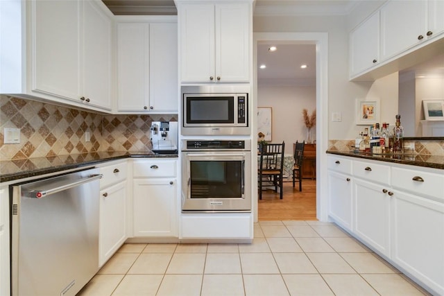 kitchen featuring light tile patterned floors, white cabinetry, appliances with stainless steel finishes, and dark stone counters