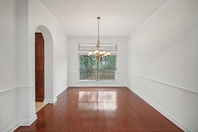 spare room featuring dark wood-type flooring and a notable chandelier