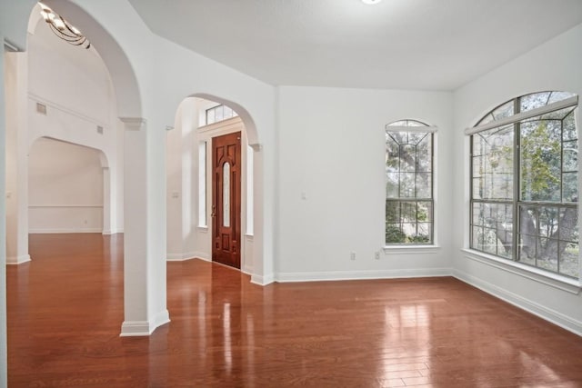 entrance foyer featuring a notable chandelier, plenty of natural light, and dark wood-type flooring