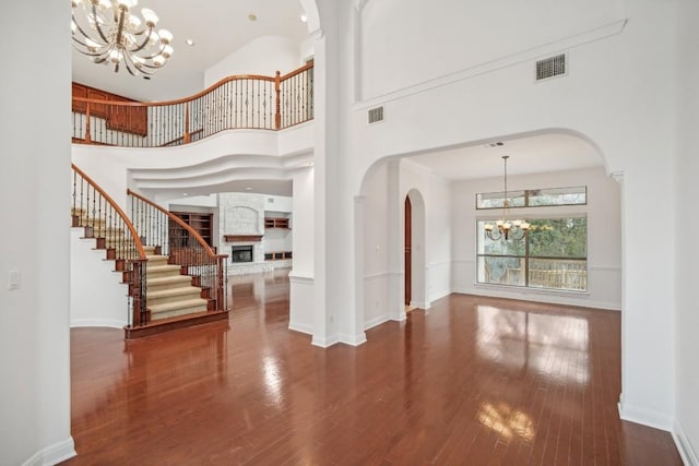 entrance foyer featuring an inviting chandelier, a towering ceiling, and hardwood / wood-style flooring