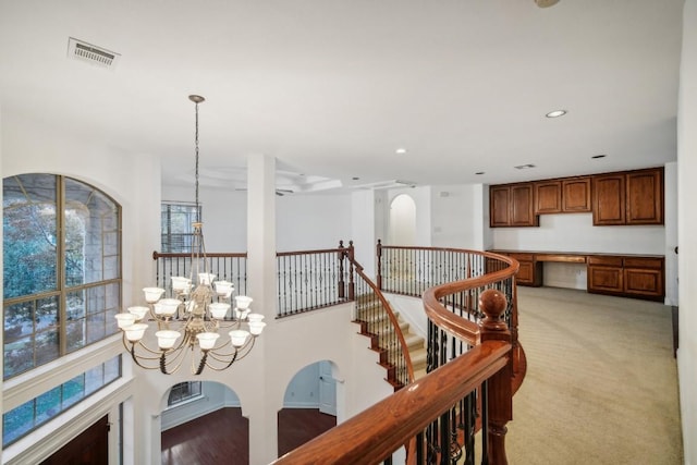 hall with light colored carpet and a notable chandelier