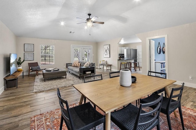 dining room with ceiling fan, french doors, wood-type flooring, and a textured ceiling