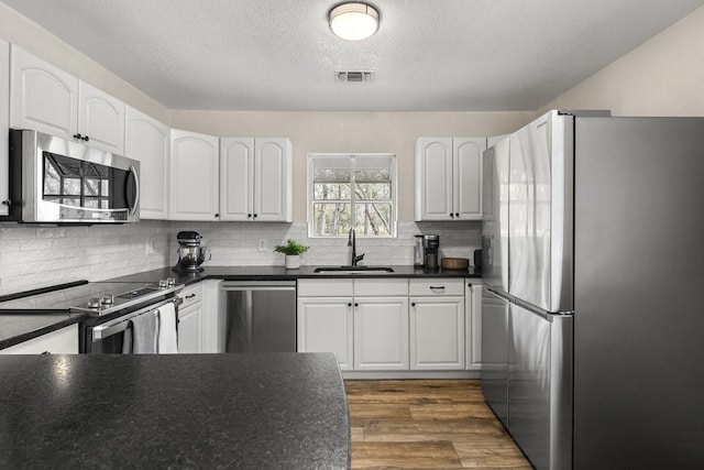 kitchen featuring white cabinets, appliances with stainless steel finishes, dark hardwood / wood-style floors, and sink