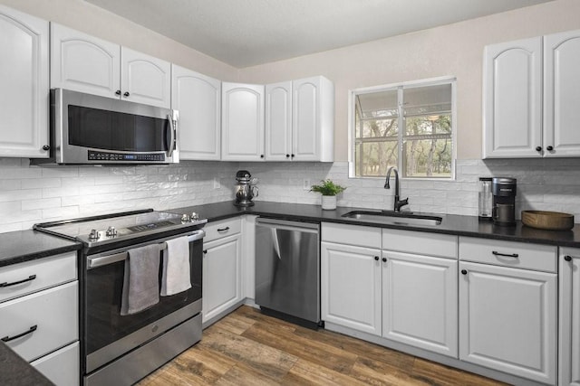 kitchen featuring sink, dark hardwood / wood-style floors, backsplash, white cabinets, and appliances with stainless steel finishes