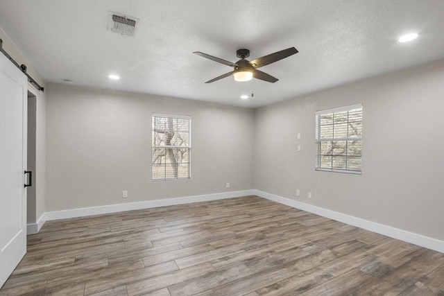 empty room featuring hardwood / wood-style flooring, a barn door, and a wealth of natural light