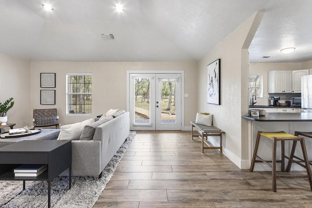 living room with french doors, sink, a textured ceiling, and dark hardwood / wood-style floors