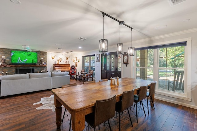 dining space with a large fireplace, crown molding, and dark hardwood / wood-style flooring