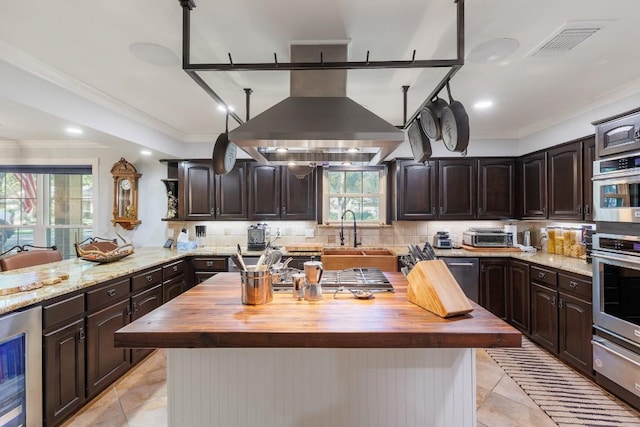 kitchen featuring wooden counters, island range hood, beverage cooler, sink, and a kitchen island