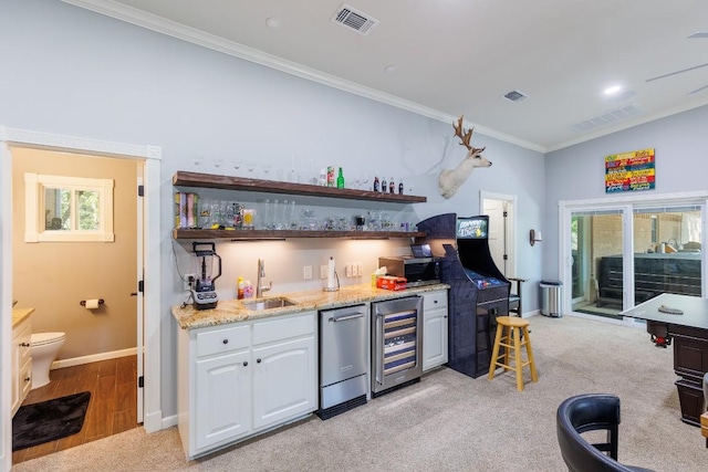 kitchen featuring sink, ornamental molding, appliances with stainless steel finishes, light colored carpet, and beverage cooler