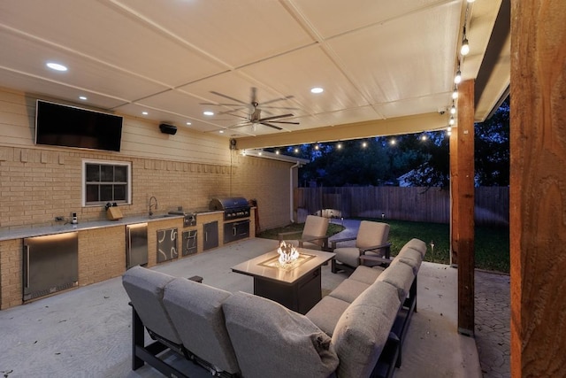 view of patio featuring a fire pit, grilling area, sink, ceiling fan, and exterior kitchen