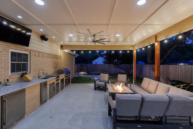 view of patio / terrace featuring grilling area, an outdoor kitchen, sink, ceiling fan, and an outdoor fire pit