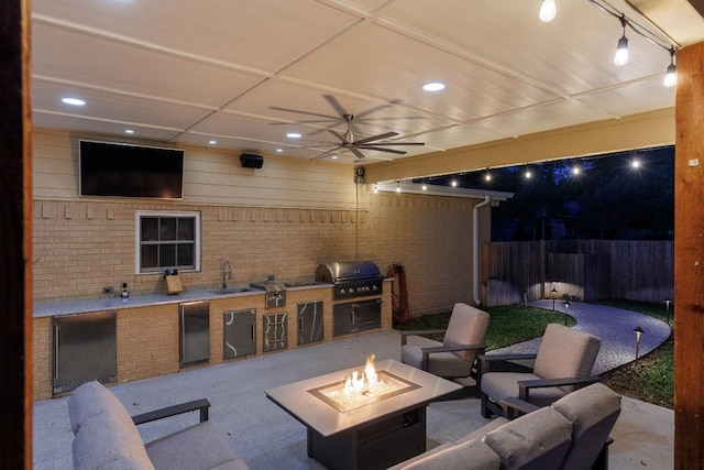 view of patio featuring ceiling fan, sink, exterior kitchen, an outdoor fire pit, and a grill