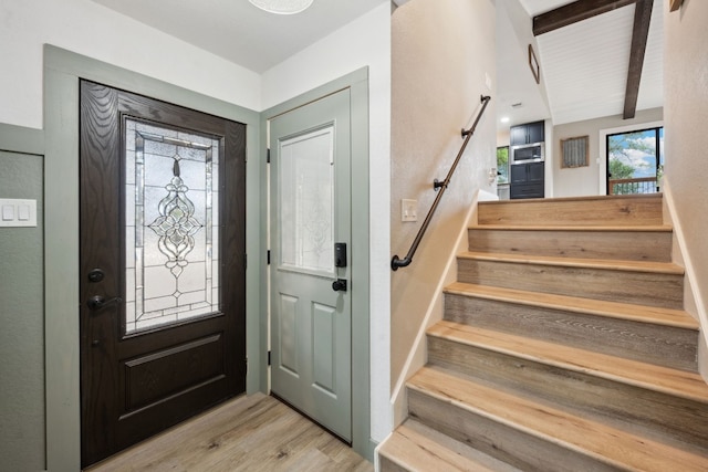 entryway featuring beamed ceiling and light wood-type flooring