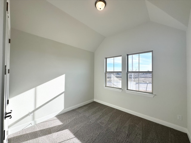 carpeted empty room featuring vaulted ceiling