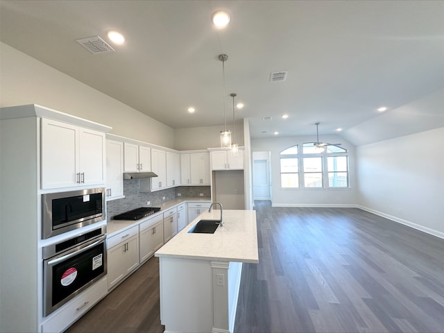 kitchen with white cabinets, lofted ceiling, stainless steel appliances, sink, and light stone counters