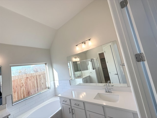 bathroom featuring plus walk in shower, vaulted ceiling, and vanity