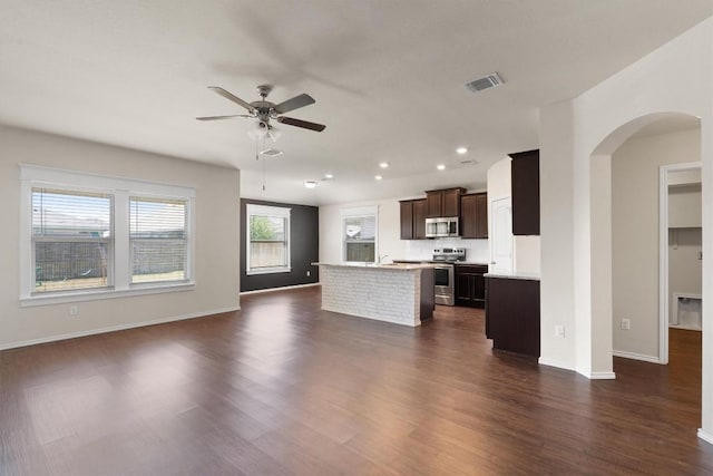 kitchen with ceiling fan, a kitchen island, dark hardwood / wood-style flooring, and stainless steel appliances