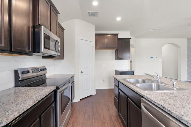 kitchen with backsplash, dark wood-type flooring, sink, light stone countertops, and appliances with stainless steel finishes