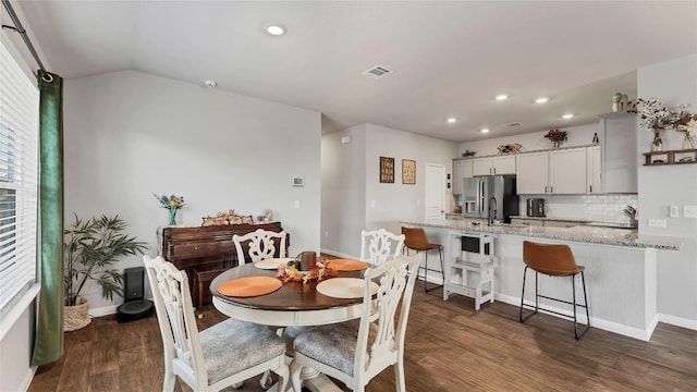 dining room featuring dark wood-type flooring and vaulted ceiling