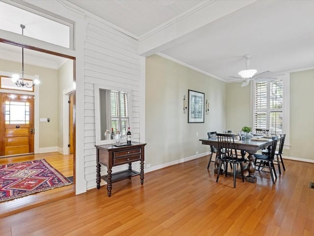 dining area featuring ceiling fan with notable chandelier, a healthy amount of sunlight, wood-type flooring, and crown molding