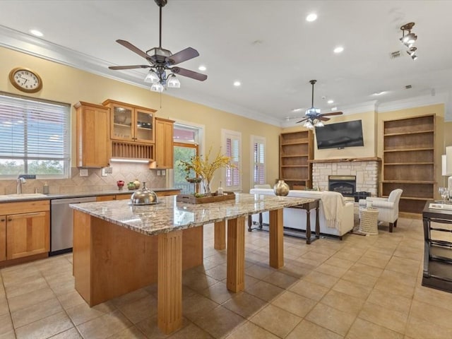 kitchen featuring stainless steel dishwasher, a kitchen island, a fireplace, and a wealth of natural light