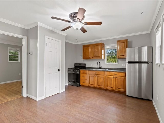 kitchen featuring black gas range, stainless steel refrigerator, plenty of natural light, and sink