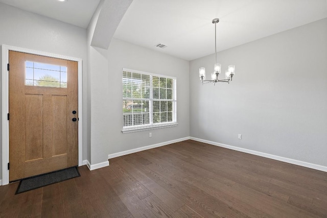 foyer entrance with plenty of natural light, dark hardwood / wood-style floors, and an inviting chandelier