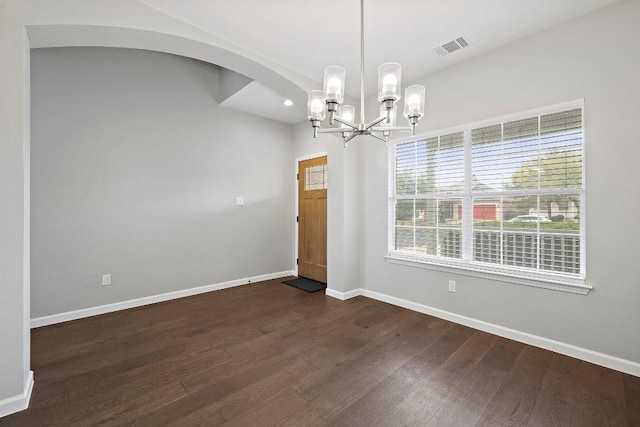 spare room featuring dark hardwood / wood-style flooring and a notable chandelier