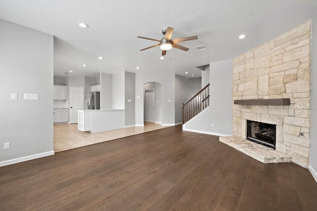 unfurnished living room featuring a stone fireplace, ceiling fan, and light hardwood / wood-style flooring