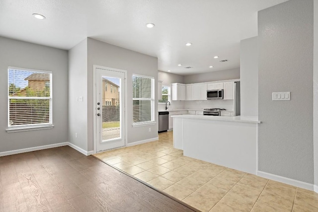 kitchen featuring light hardwood / wood-style floors, a healthy amount of sunlight, white cabinetry, and stainless steel appliances