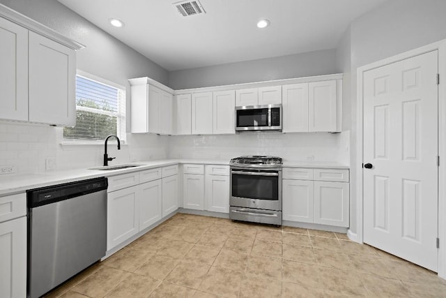 kitchen with white cabinets, sink, decorative backsplash, light tile patterned flooring, and stainless steel appliances