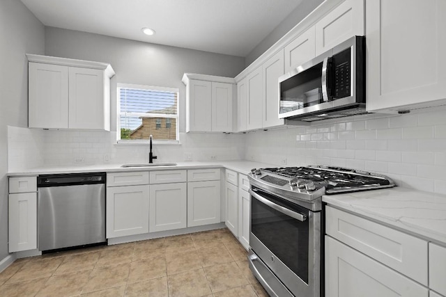 kitchen featuring white cabinets, appliances with stainless steel finishes, light tile patterned flooring, and sink