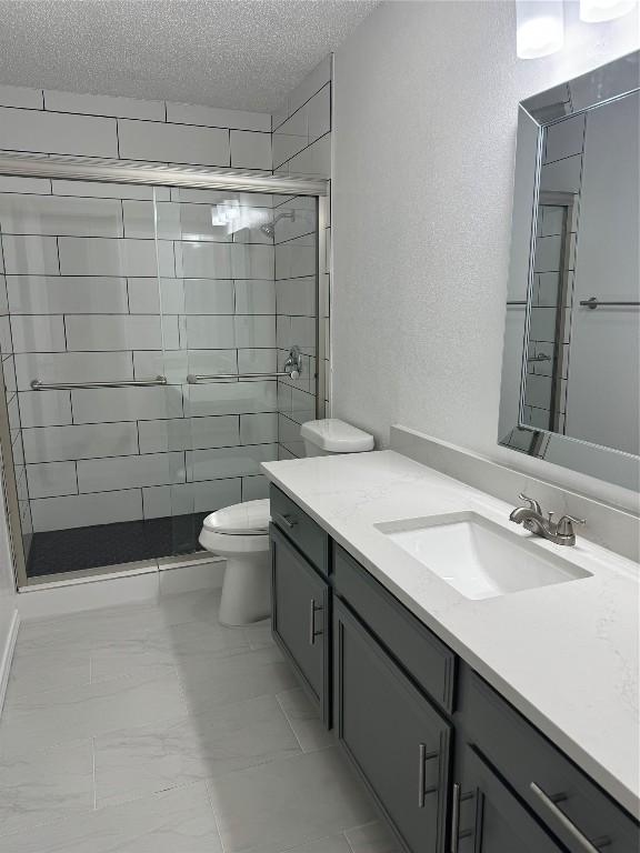 bathroom with vanity, toilet, a textured ceiling, and walk in shower