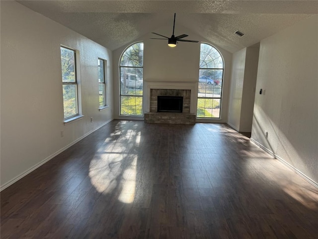 unfurnished living room featuring dark hardwood / wood-style flooring, a textured ceiling, vaulted ceiling, ceiling fan, and a fireplace