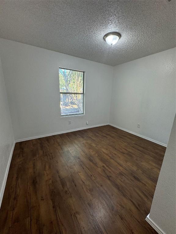 unfurnished room featuring a textured ceiling and dark wood-type flooring