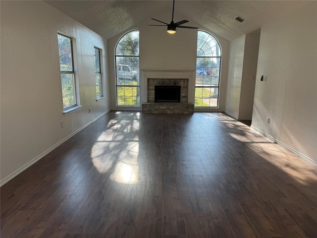 unfurnished living room with a fireplace, a textured ceiling, vaulted ceiling, and dark wood-type flooring