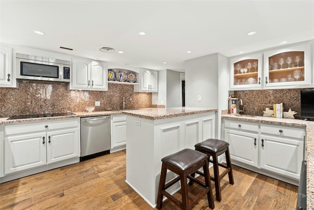 kitchen with white cabinetry, stainless steel appliances, and light wood-type flooring