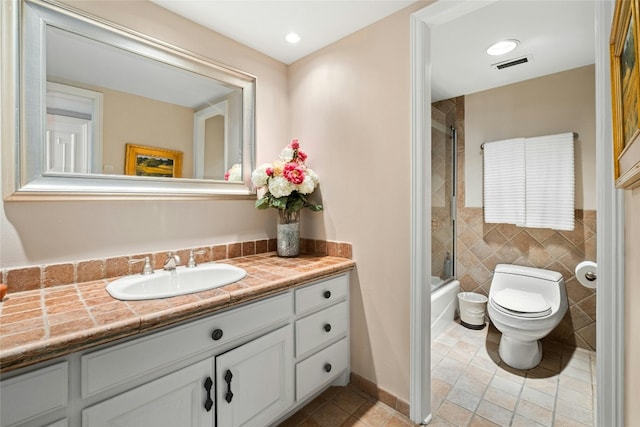 full bathroom with vanity, tile patterned flooring, toilet, enclosed tub / shower combo, and tile walls