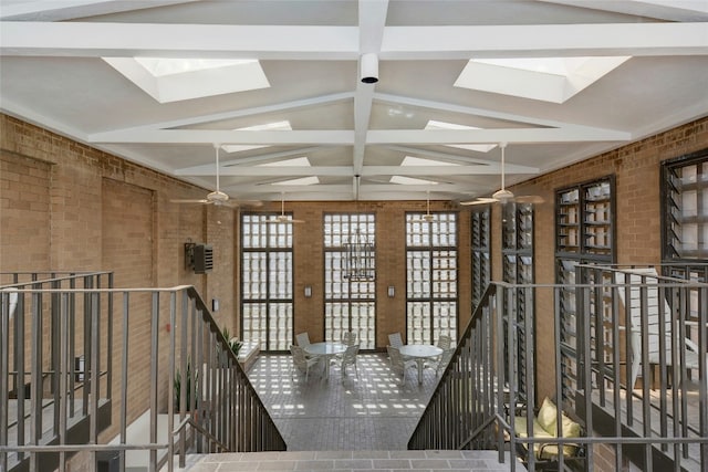 misc room with vaulted ceiling with skylight and brick wall