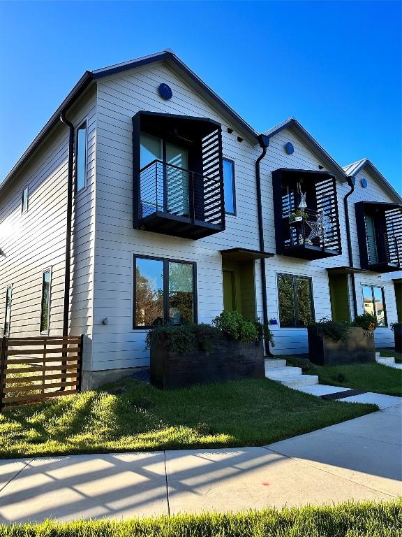 view of front of property featuring a balcony and a front lawn