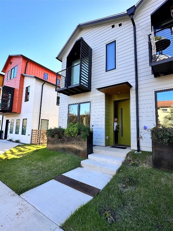 view of front of property with a balcony and a front lawn