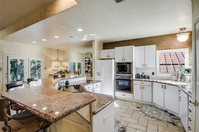 kitchen featuring a kitchen bar, white cabinets, black appliances, and a kitchen island