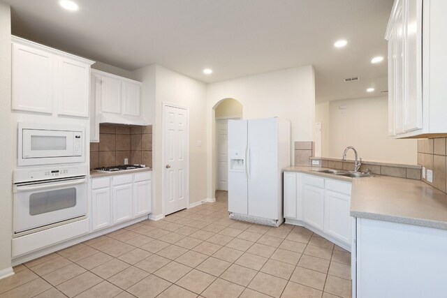 kitchen with white appliances, backsplash, white cabinetry, and sink