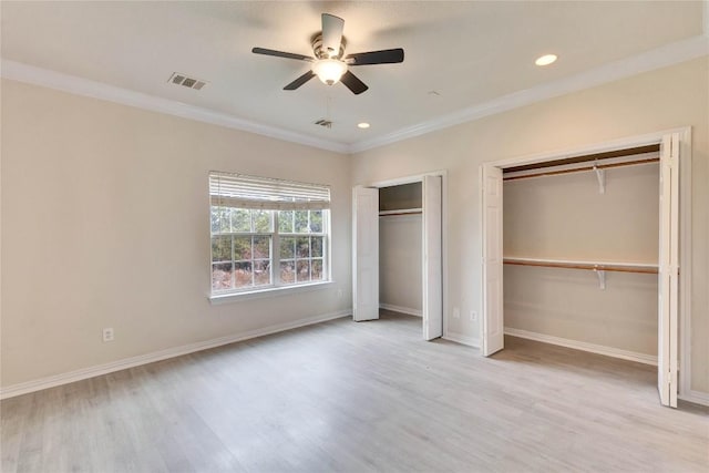 unfurnished bedroom with ceiling fan, light hardwood / wood-style floors, two closets, and ornamental molding