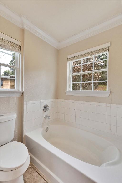 bathroom with a bathtub, tile patterned flooring, ornamental molding, and toilet